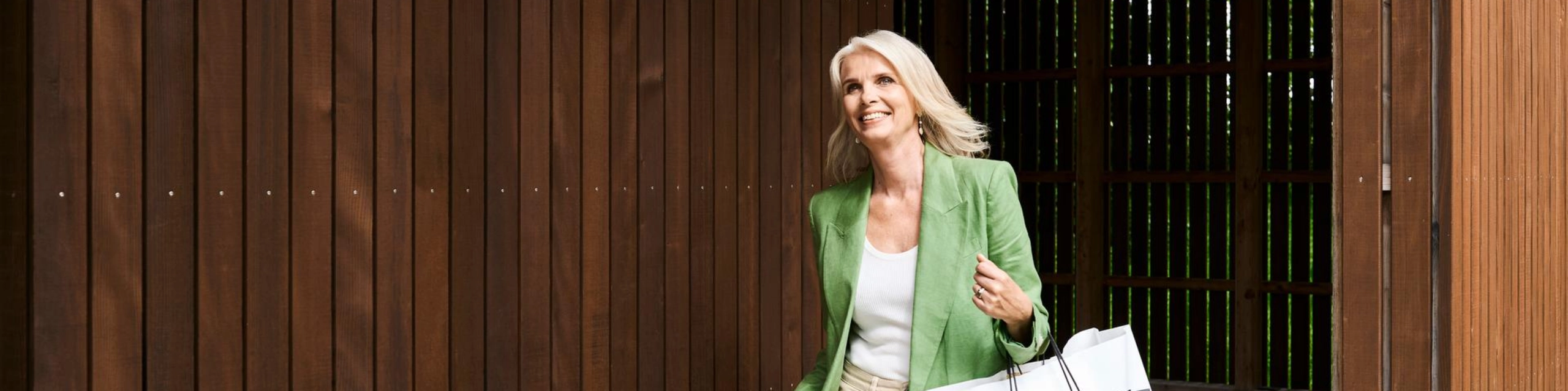 Frau mit Einkaufstaschen verlässt ein Gebäude - Ausdruck für die neue finanzielle Freiheit nach Ablösen eines Kredites. 