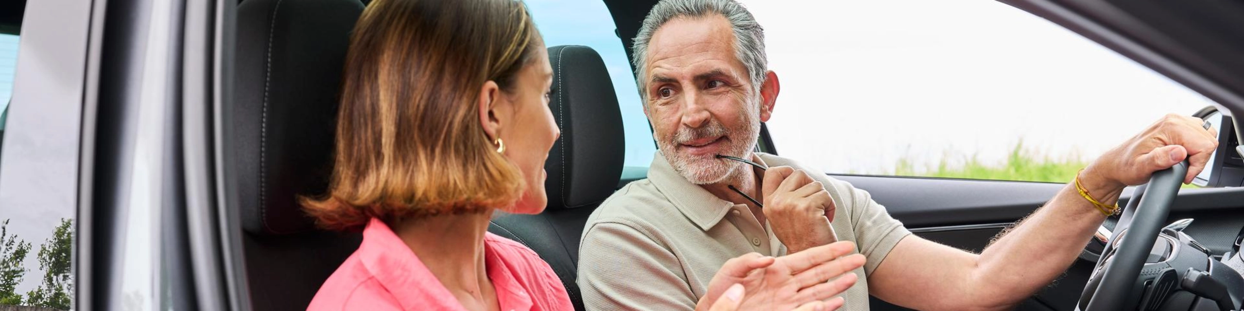 Conversa entre um homem e uma mulher no carro, simbolizando uma parceria no leasing