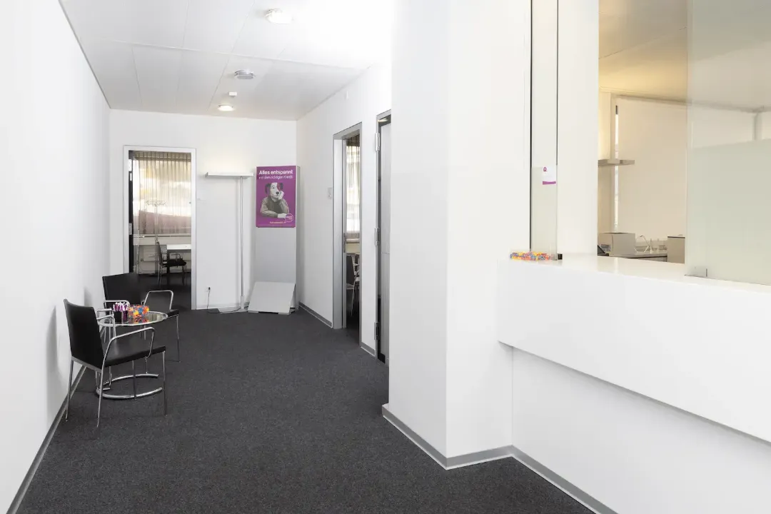 Área de atendimento da filial BANK-now Zurique-Oerlikon com interior claro e cartaz ao fundo.