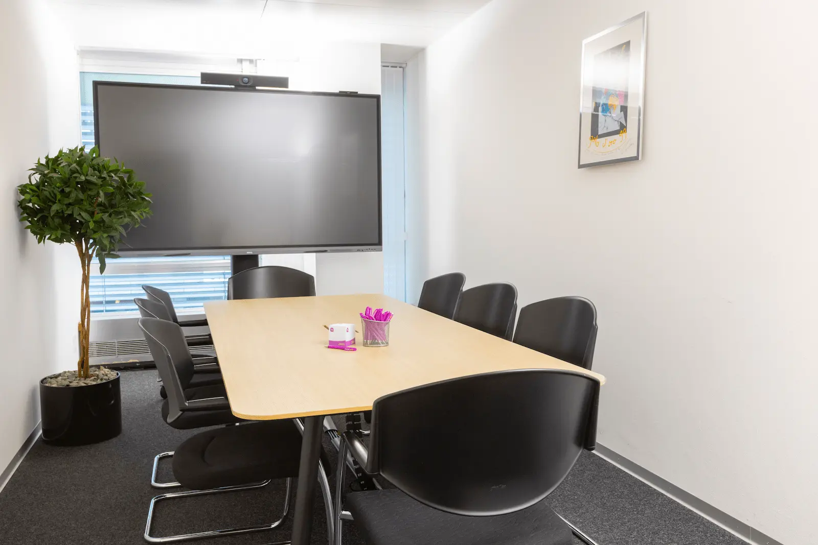 Sala de reunião da filial BANK-now Zurique com mesa redonda, cadeiras e grande janela.