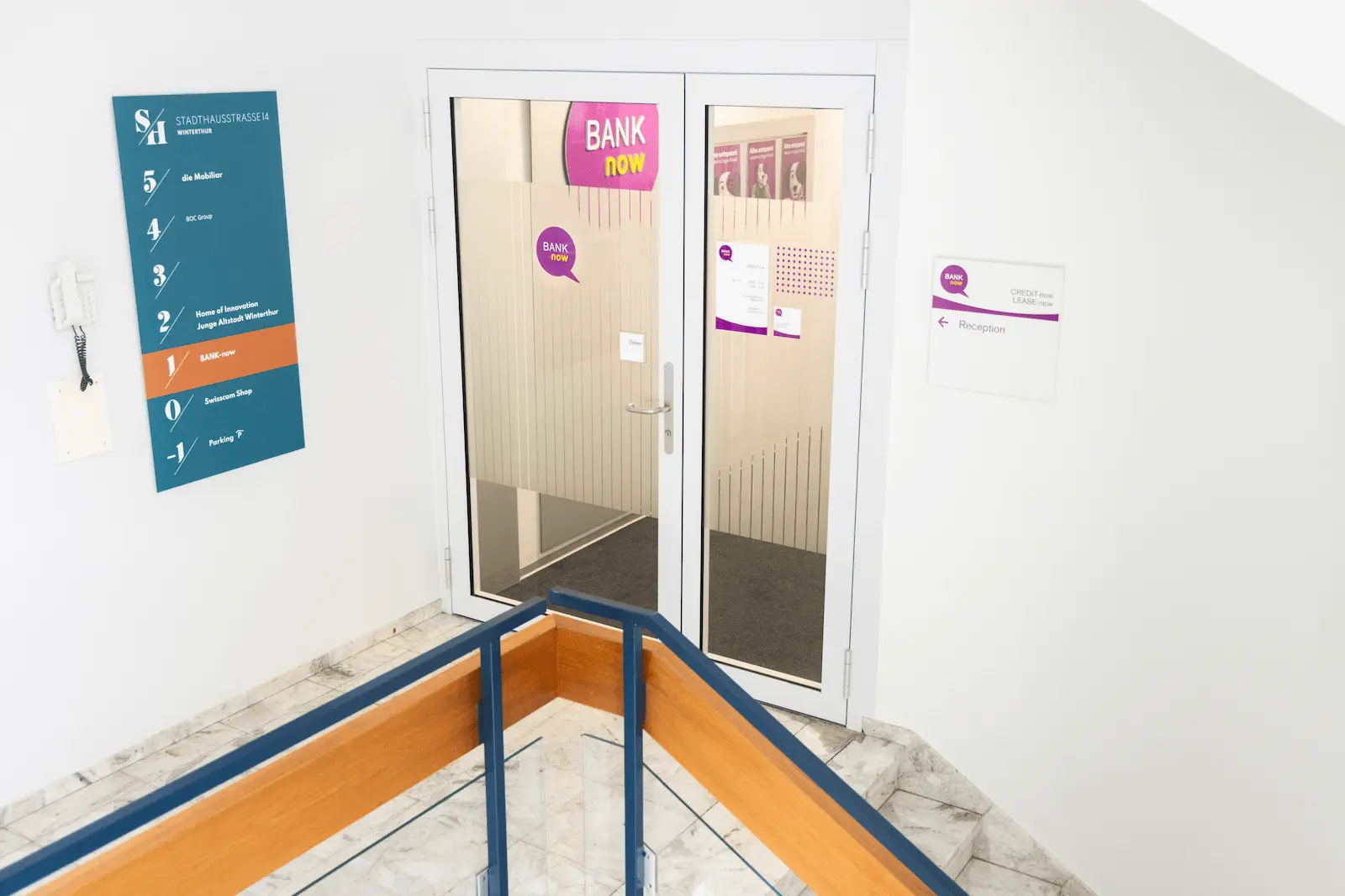 Entrada interior da filial BANK-now Winterthur com sinalização e porta de vidro.