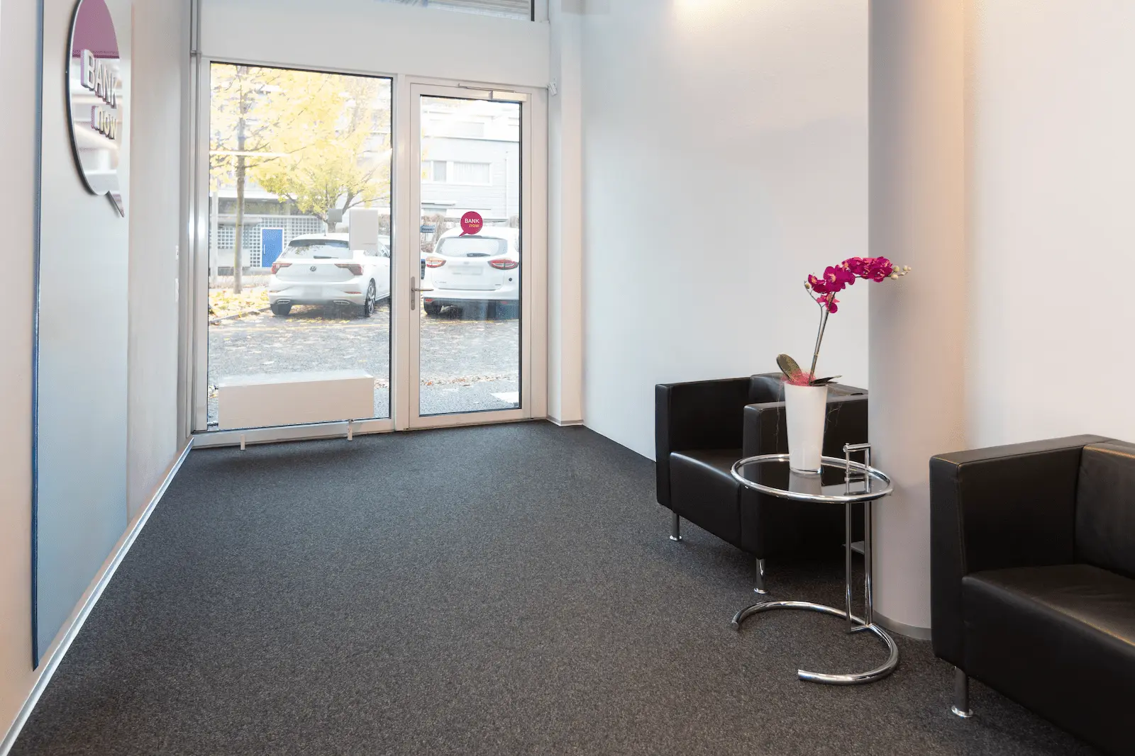 Heller Eingangsbereich der BANK-now Filiale Uster mit zwei Sesseln, Tisch und grossen Fenstern.