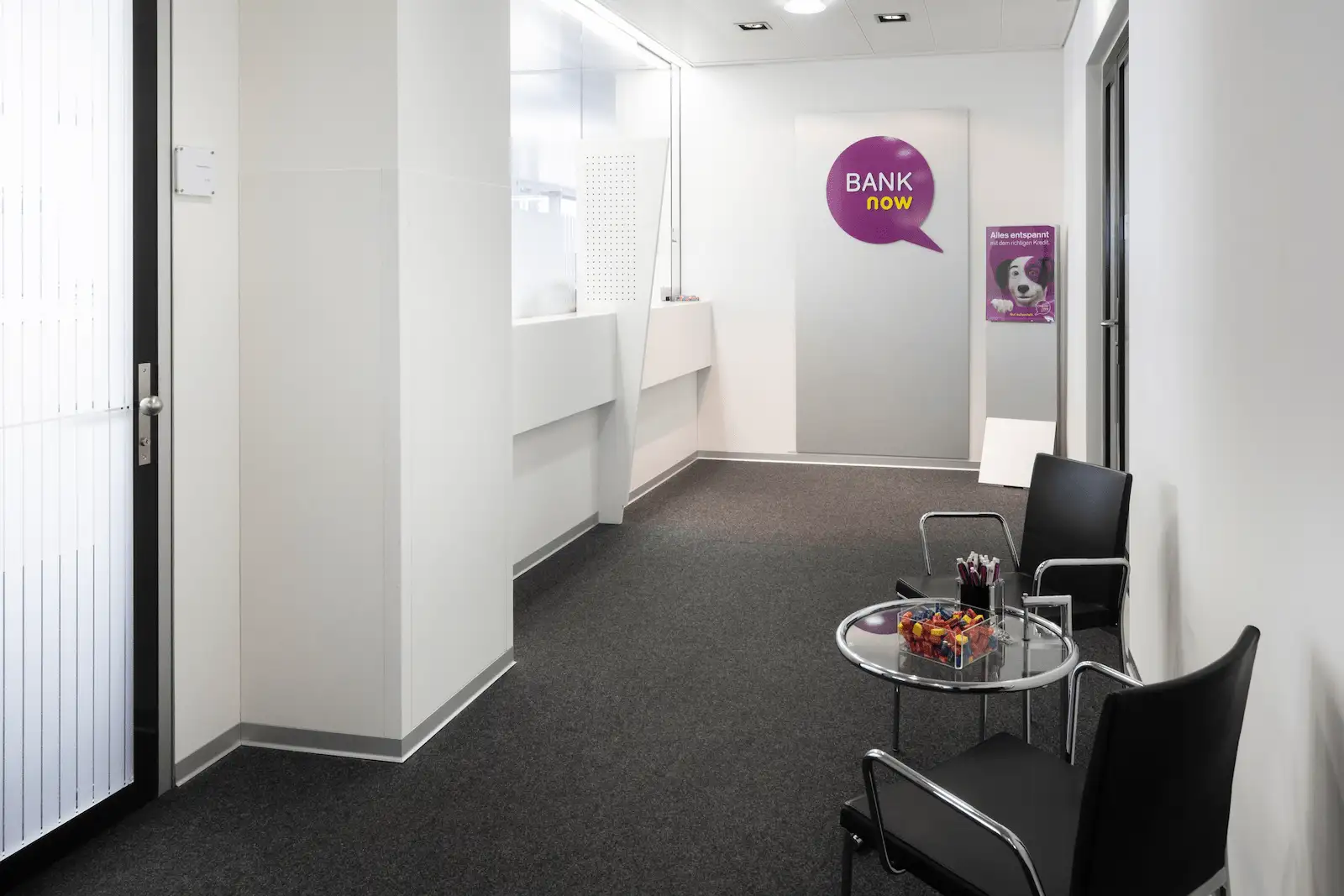 Entrada interior da filial BANK-now Zurique-Oerlikon com zona de espera e espaço luminoso.